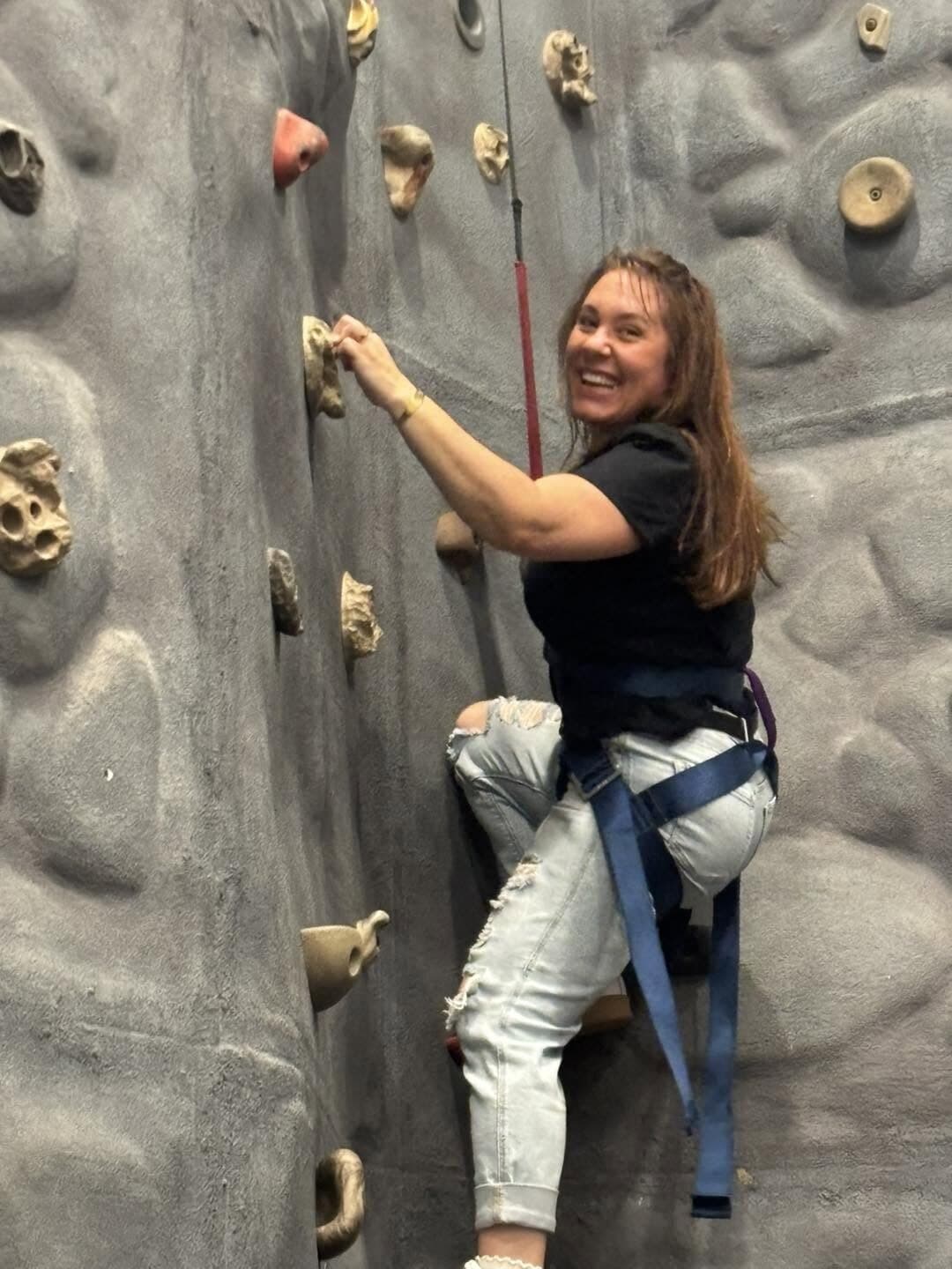 Smiling on the climbing wall during a Rise Above outing
