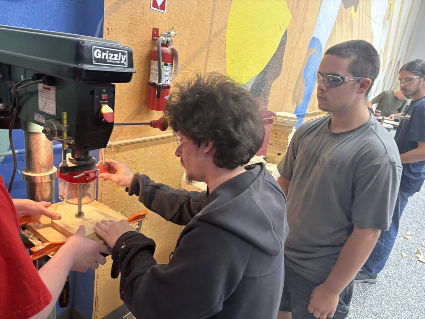 Rise Above students working together at a drill press in the shop